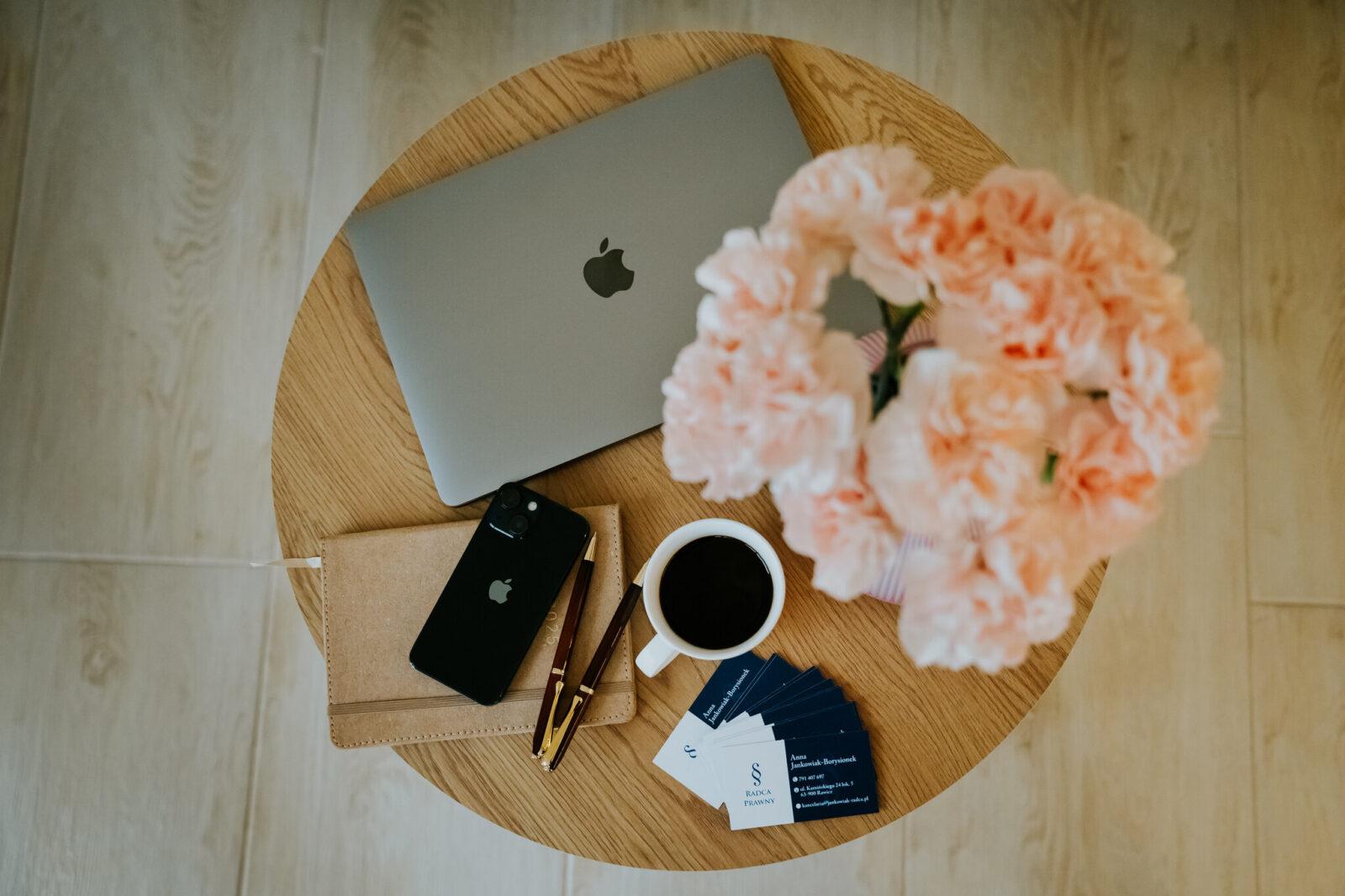 A woman in a business suit working at a desk with a laptop and papers in an office.